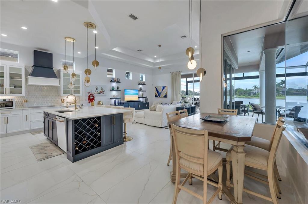 8957 Shenendoah Circle Naples, FL 34113 - Photo 15 of 50 a kitchen with stainless steel appliances kitchen island granite countertop a table chairs sink and wooden cabinets