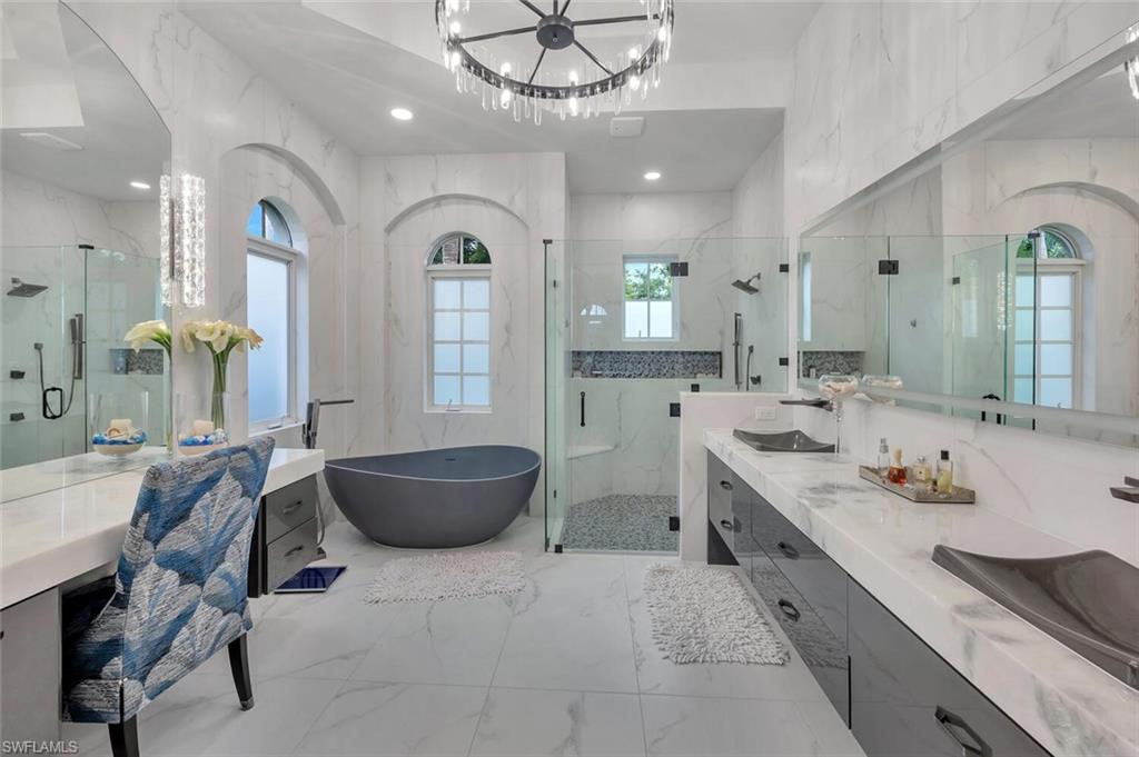 8957 Shenendoah Circle Naples, FL 34113 - Photo 30 of 50 a large bathroom with a granite countertop sink a large mirror and a bathtub