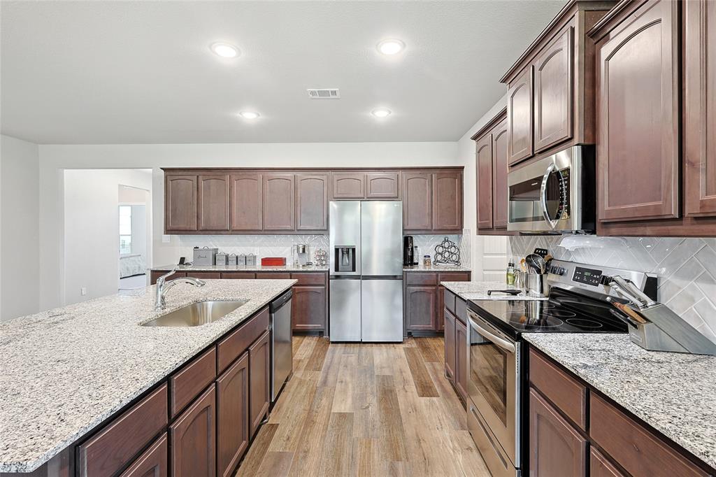 808 Feather Edge Drive Springtown, TX 76082 - Photo 15 of 40 a kitchen with kitchen island granite countertop a sink stove microwave and refrigerator