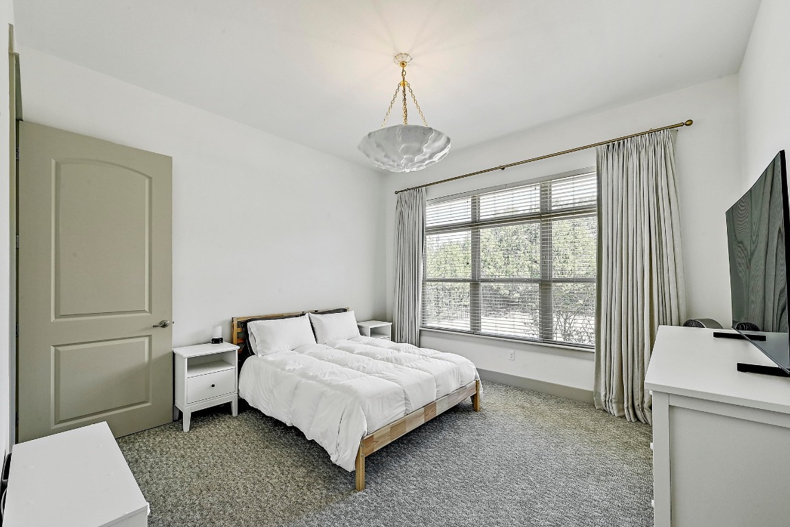 7909 Orisha Drive Austin, TX 78739 - Photo 32 of 40 a bedroom with a bed and a flat tv screen on the dresser