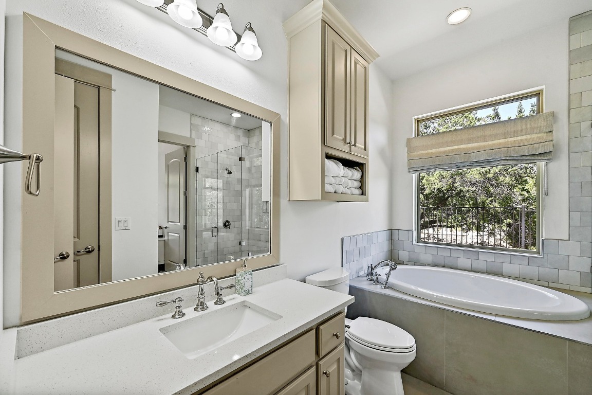 7909 Orisha Drive Austin, TX 78739 - Photo 33 of 40 a bathroom with a bathtub shower sink vanity mirror and toilet