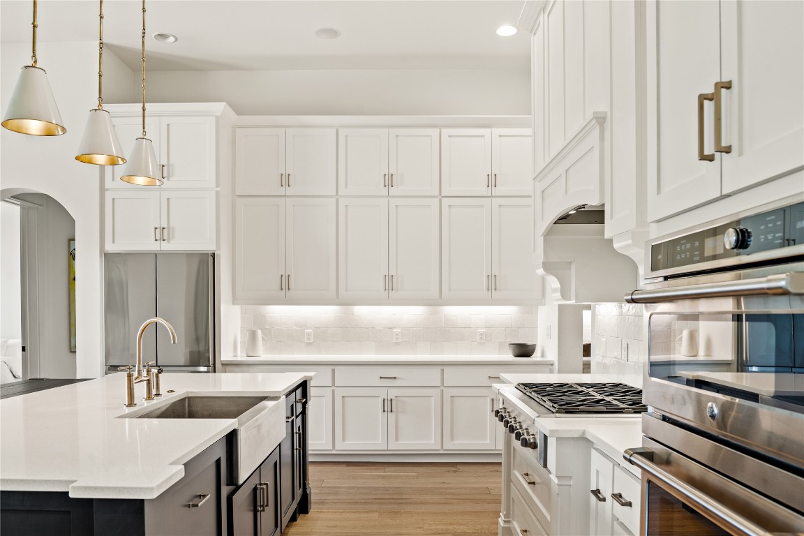 7909 Orisha Drive Austin, TX 78739 - Photo 8 of 40 a kitchen with stainless steel appliances granite countertop a sink stove oven and white cabinets with wooden floor