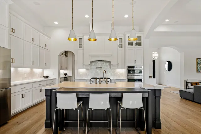 a kitchen with kitchen island granite countertop a sink and white cabinets with wooden floor