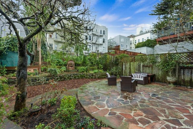 a view of a patio with table and chairs potted plants and large tree