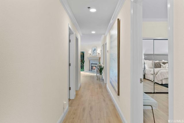 a view of a hallway with wooden floor and a bathroom