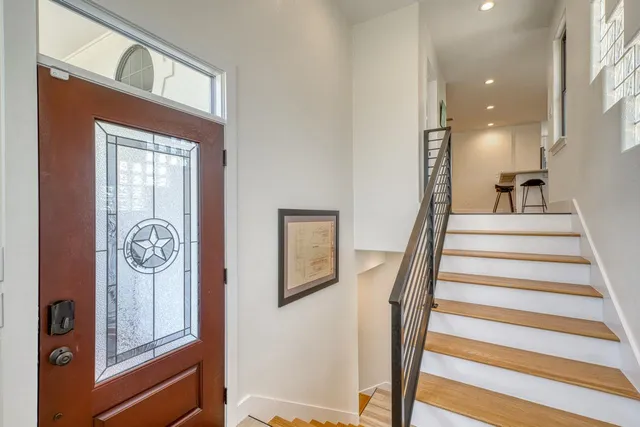 a living room with furniture large windows and wooden floor