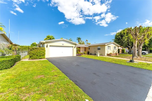 a yellow and red house with a big yard and large trees