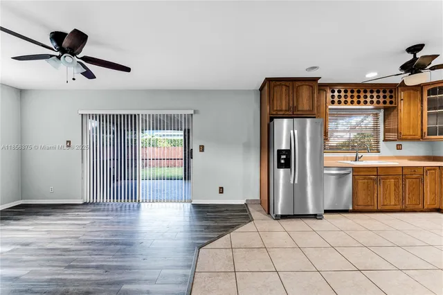 a open kitchen with stainless steel appliances granite countertop a stove a sink dishwasher and a refrigerator with wooden floor