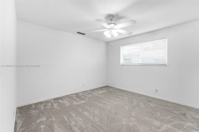 an empty room with a chandelier fan and windows