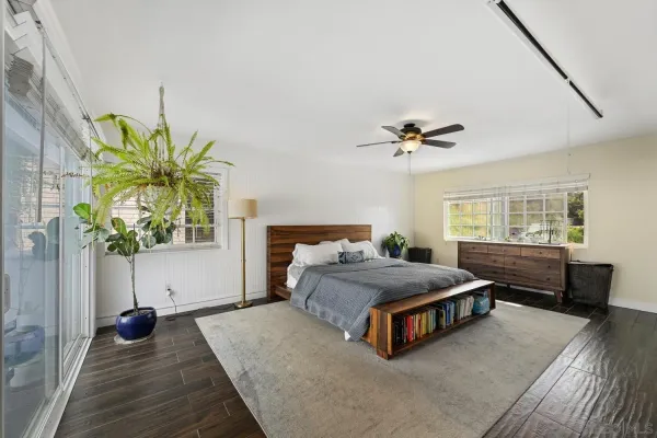 a bedroom with a bed potted plant with the wooden floor