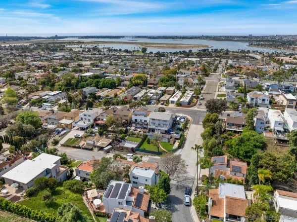 an aerial view of a city with lots of residential buildings and ocean view in back
