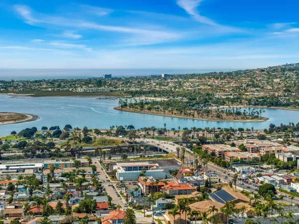 an aerial view of a city with lots of residential buildings and ocean view in back