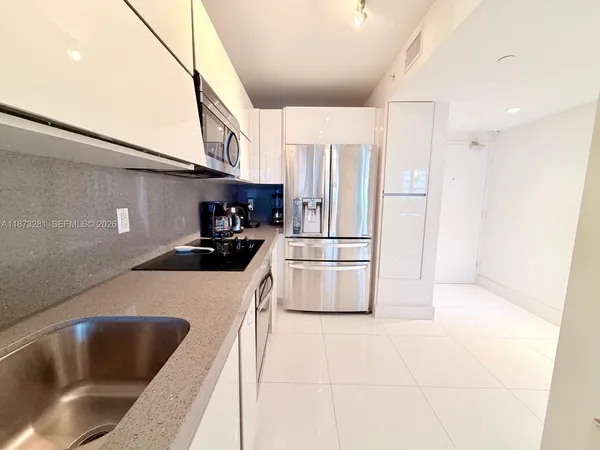 a kitchen with stainless steel appliances a refrigerator a sink a stove and white cabinets