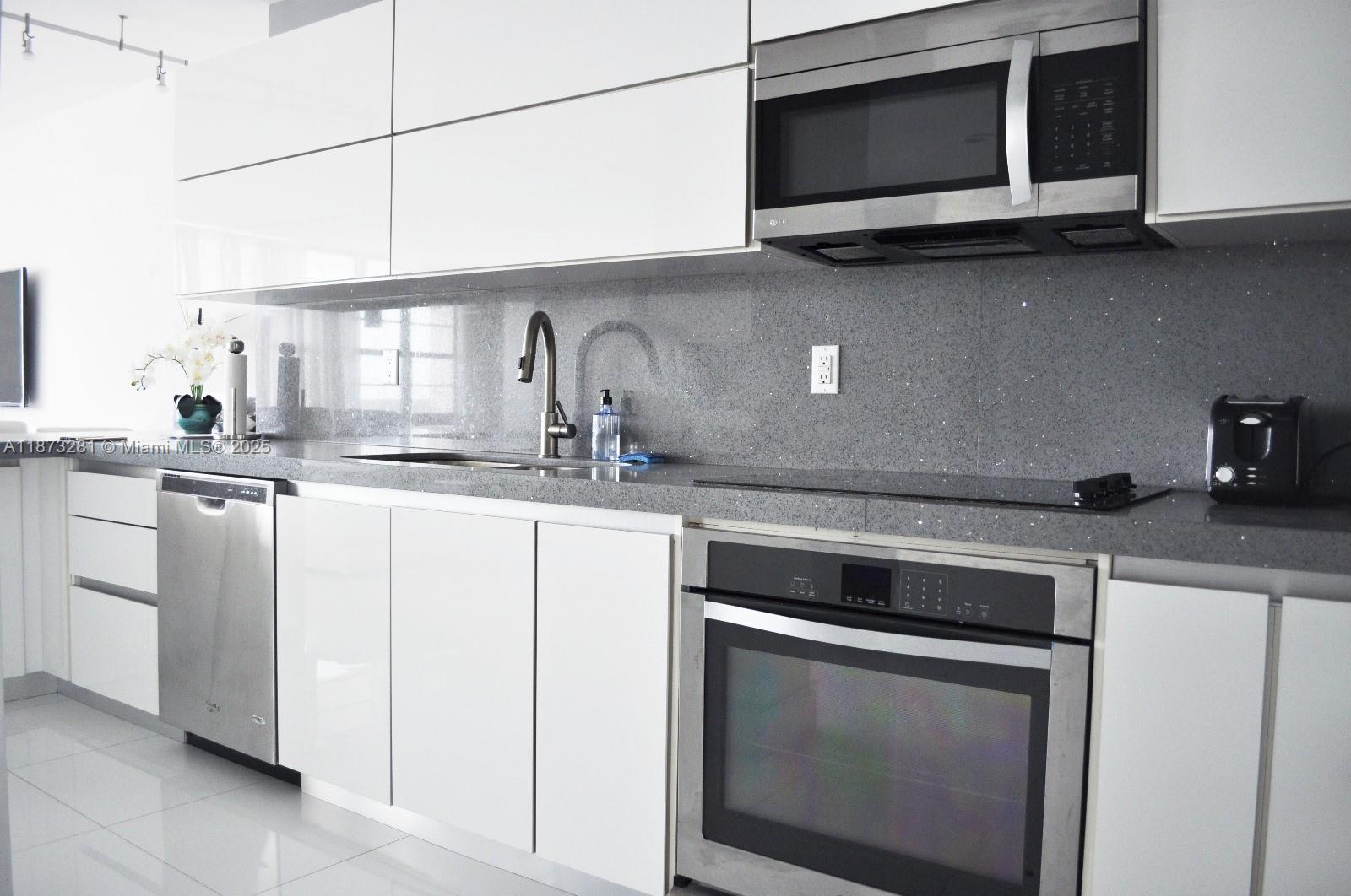 100 Lincoln Road, Unit 1504 Miami Beach, FL 33139 - Photo 5 of 12 a kitchen with stainless steel appliances granite countertop a stove microwave and sink