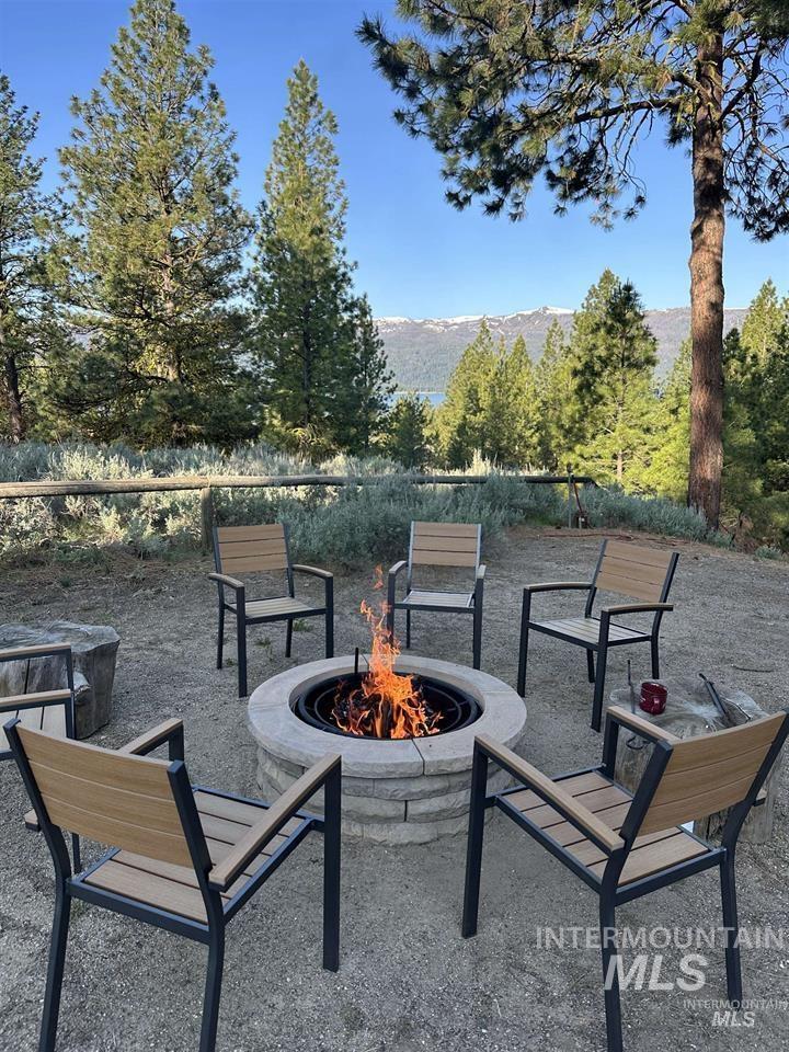21 Melonie Loop Cascade, ID 83611 - Photo 6 of 27 Outdoor fire pit area featuring a stone block fire pit, surrounding seating, and a natural landscape with mature trees