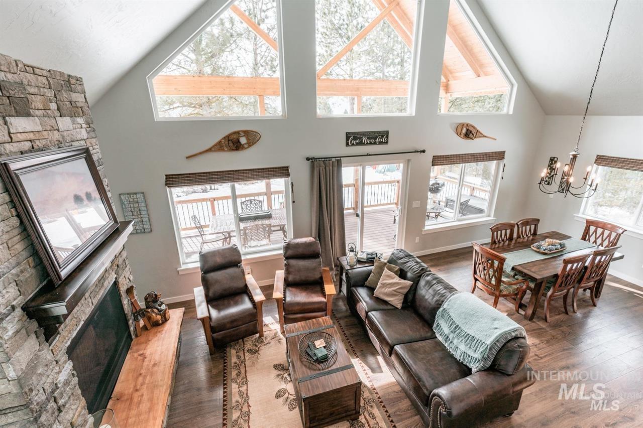 21 Melonie Loop Cascade, ID 83611 - Photo 8 of 27 Vaulted ceiling great room featuring a stone fireplace with wood mantle, wood-finish flooring, and multiple windows including upper triangular windows