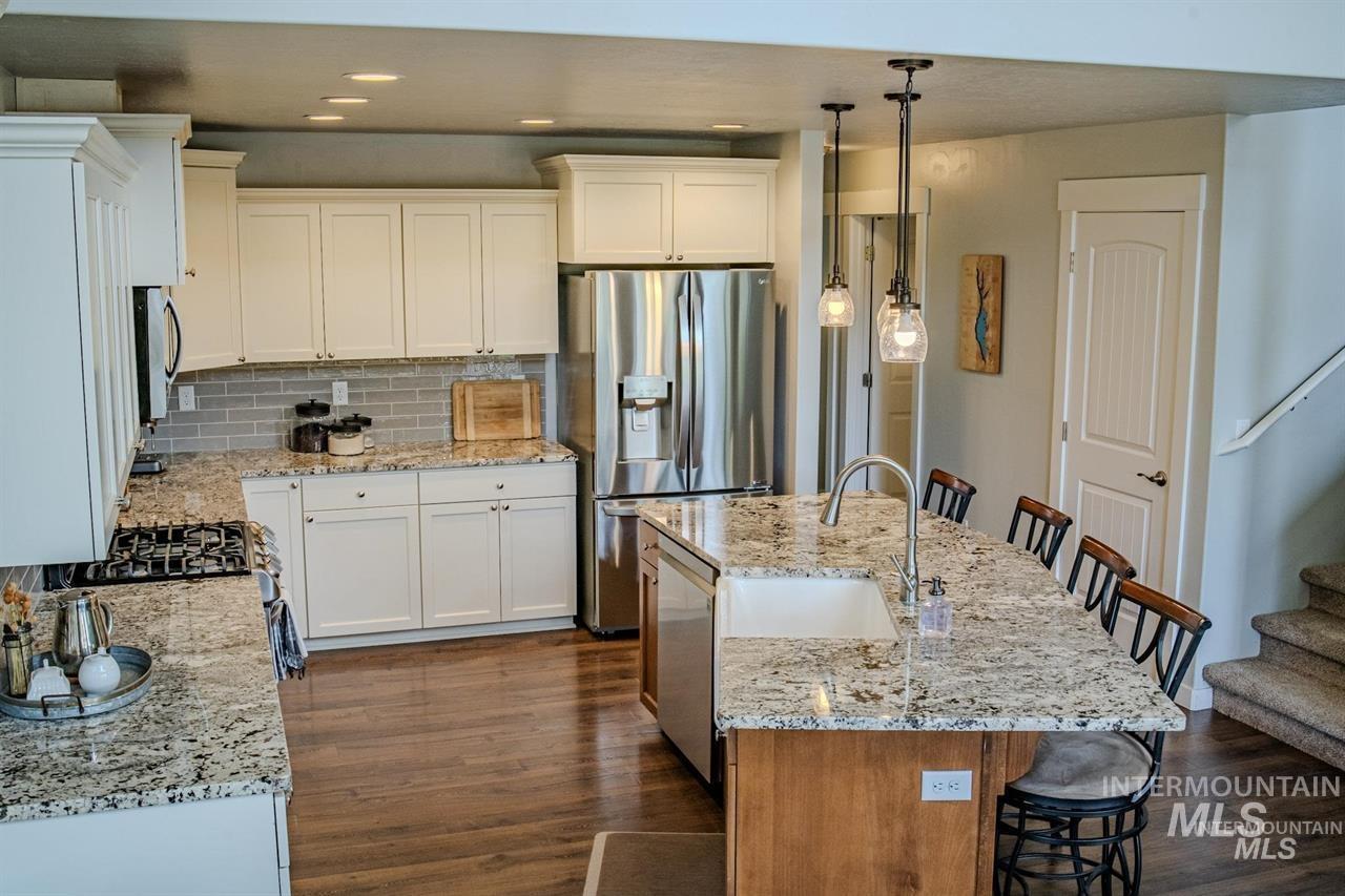 21 Melonie Loop Cascade, ID 83611 - Photo 9 of 27 Spacious kitchen featuring an expansive island with a farmhouse sink, stainless steel appliances, white cabinetry, and granite countertops