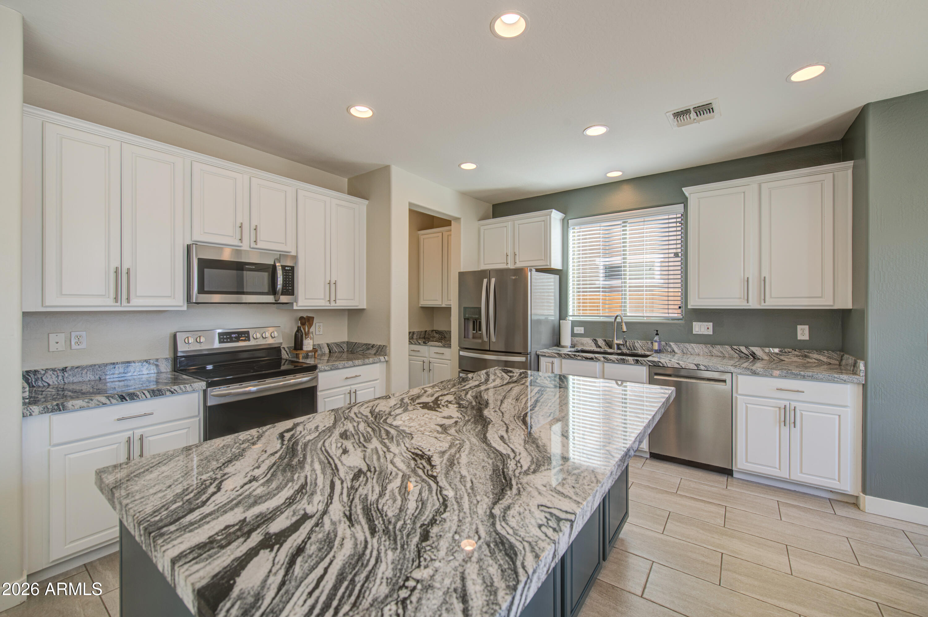21303 East Alyssa Road Queen Creek, AZ 85142 - Photo 10 of 29 a kitchen with stainless steel appliances granite countertop a stove top oven a sink dishwasher a refrigerator and white cabinets with wooden floor