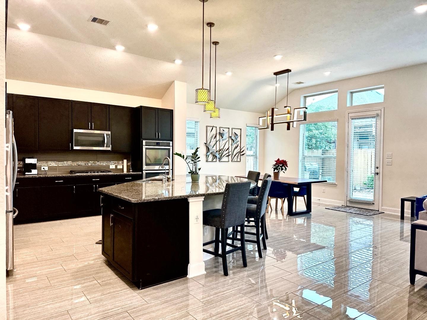 1110 Penny Ranch Lane Katy, TX 77494 - Photo 15 of 31 a kitchen with stainless steel appliances kitchen island granite countertop a stove top oven a sink a dining table and chairs with wooden floor