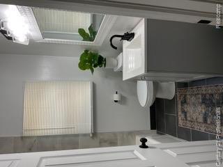 19372 Sunderland Road Detroit, MI 48219 - Photo 14 of 34 Modern bathroom featuring dark tile flooring, a white vanity with a rectangular sink, matte black faucet, and a decorative mirror