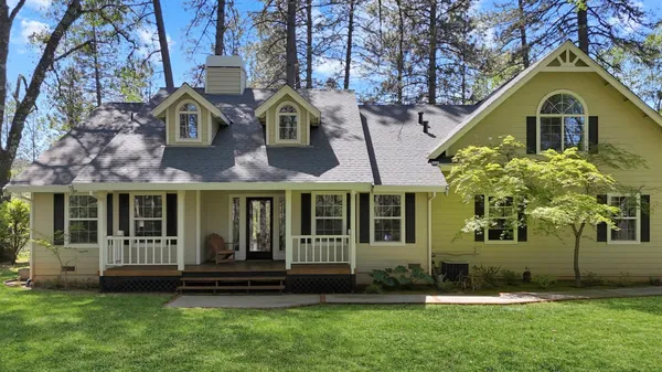 a view of a brick house with a yard and large trees