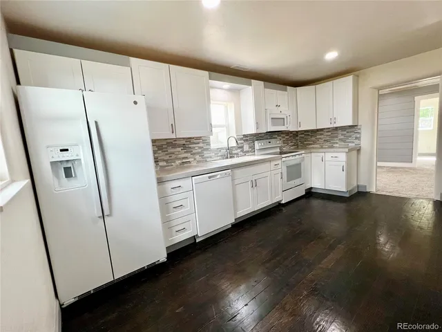 a kitchen with stainless steel appliances granite countertop a stove a sink and white cabinets