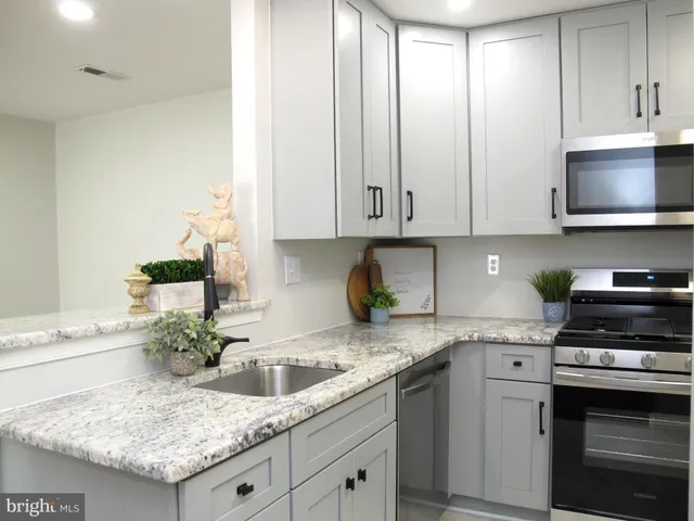 a kitchen with granite countertop a sink stainless steel appliances and cabinets