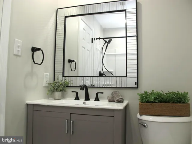 a bathroom with a granite countertop sink mirror vanity and toilet