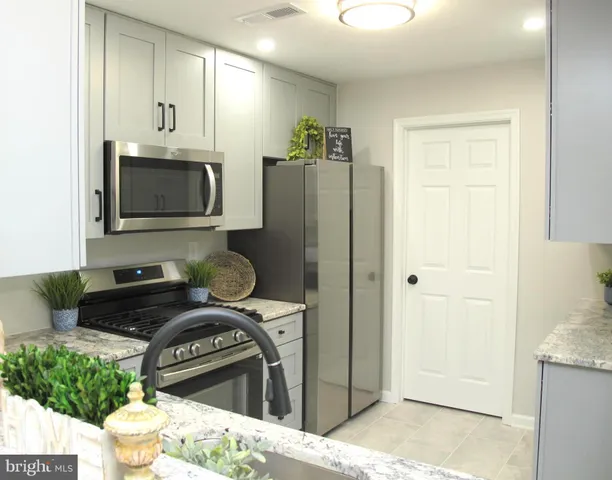 a kitchen with stainless steel appliances granite countertop a refrigerator and a stove top oven