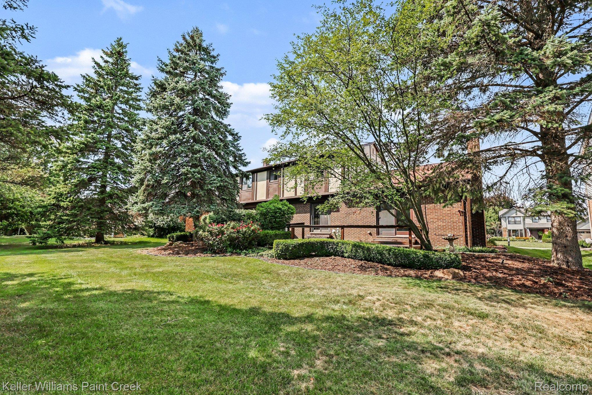 2717 Powderhorn Ridge Road Rochester, MI 48309 - Photo 35 of 48 Brick facade with integrated windows, mature trees, manicured lawn, and established landscaping