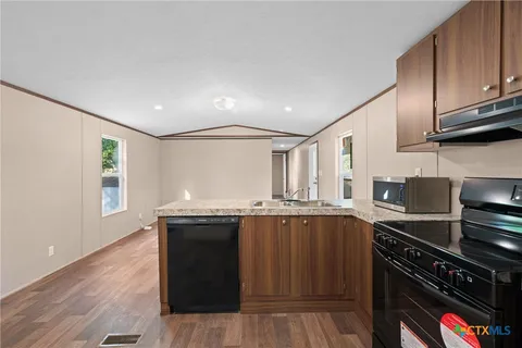 a kitchen with stainless steel appliances granite countertop a refrigerator a stove a sink and a microwave