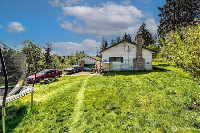 a yellow house with a big yard and large trees