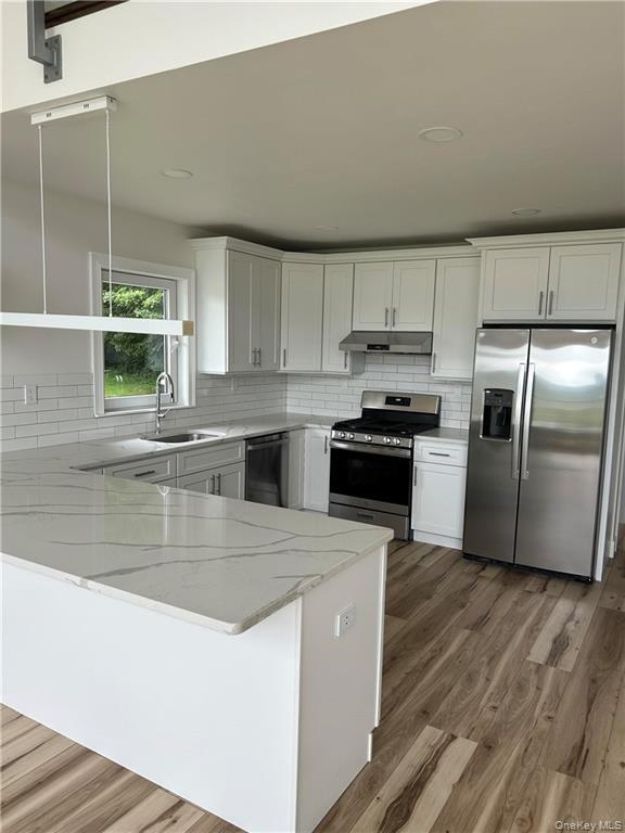 274 Reservoir Hill Road Norwich, NY 13815 - Photo 11 of 44 a kitchen with stainless steel appliances granite countertop a refrigerator a stove and a sink with wooden floor