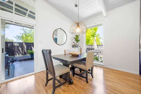 a view of a dining room with furniture a potted plant and a window