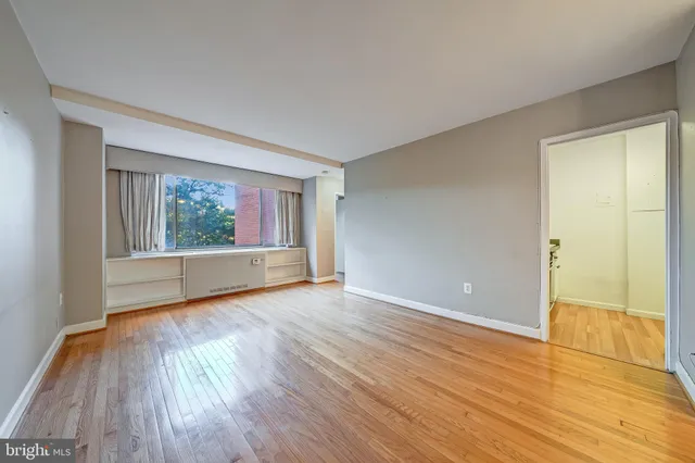 a view of an empty room with wooden floor and a window