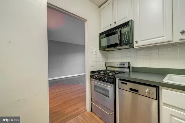 a kitchen with stainless steel appliances granite countertop white cabinets and black stove top oven with granite countertops