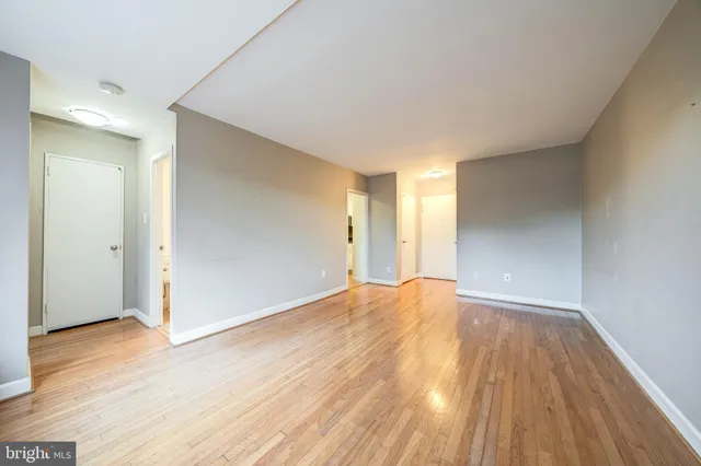 a view of an empty room with wooden floor and a window
