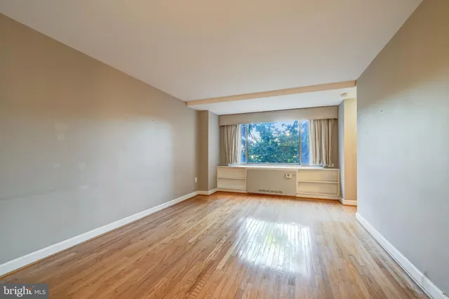 a view of an empty room with wooden floor and a window