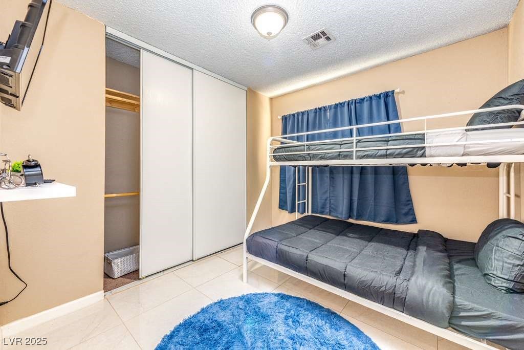 4990 Philmar Avenue Las Vegas, NV 89120 - Photo 16 of 32 Bedroom with a textured ceiling, light tile patterned floors, and a closet