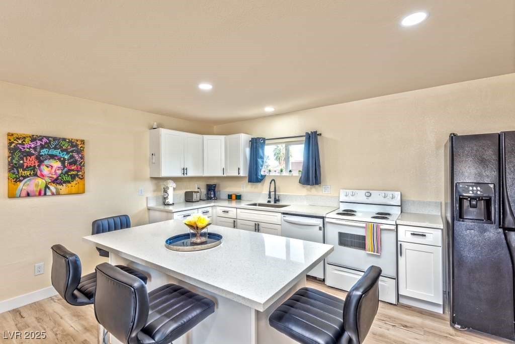 4990 Philmar Avenue Las Vegas, NV 89120 - Photo 25 of 32 White kitchen casita area, black fridge with ice dispenser, light wood finished floors, and recessed lighting