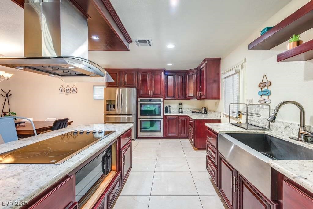 4990 Philmar Avenue Las Vegas, NV 89120 - Photo 3 of 32 Kitchen featuring dark brown cabinets, island exhaust hood, light stone counters, black appliances, and light tile patterned floors