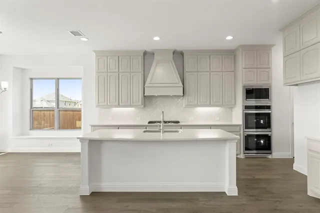 a view of kitchen with stainless steel appliances granite countertop a stove and a sink