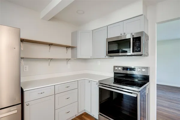 a kitchen with cabinets stainless steel appliances and a wooden floor