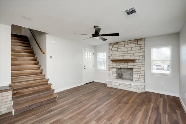 a view of an empty room with wooden floor fireplace and a window