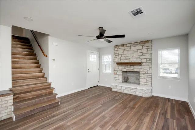 a view of an empty room with wooden floor fireplace and a window