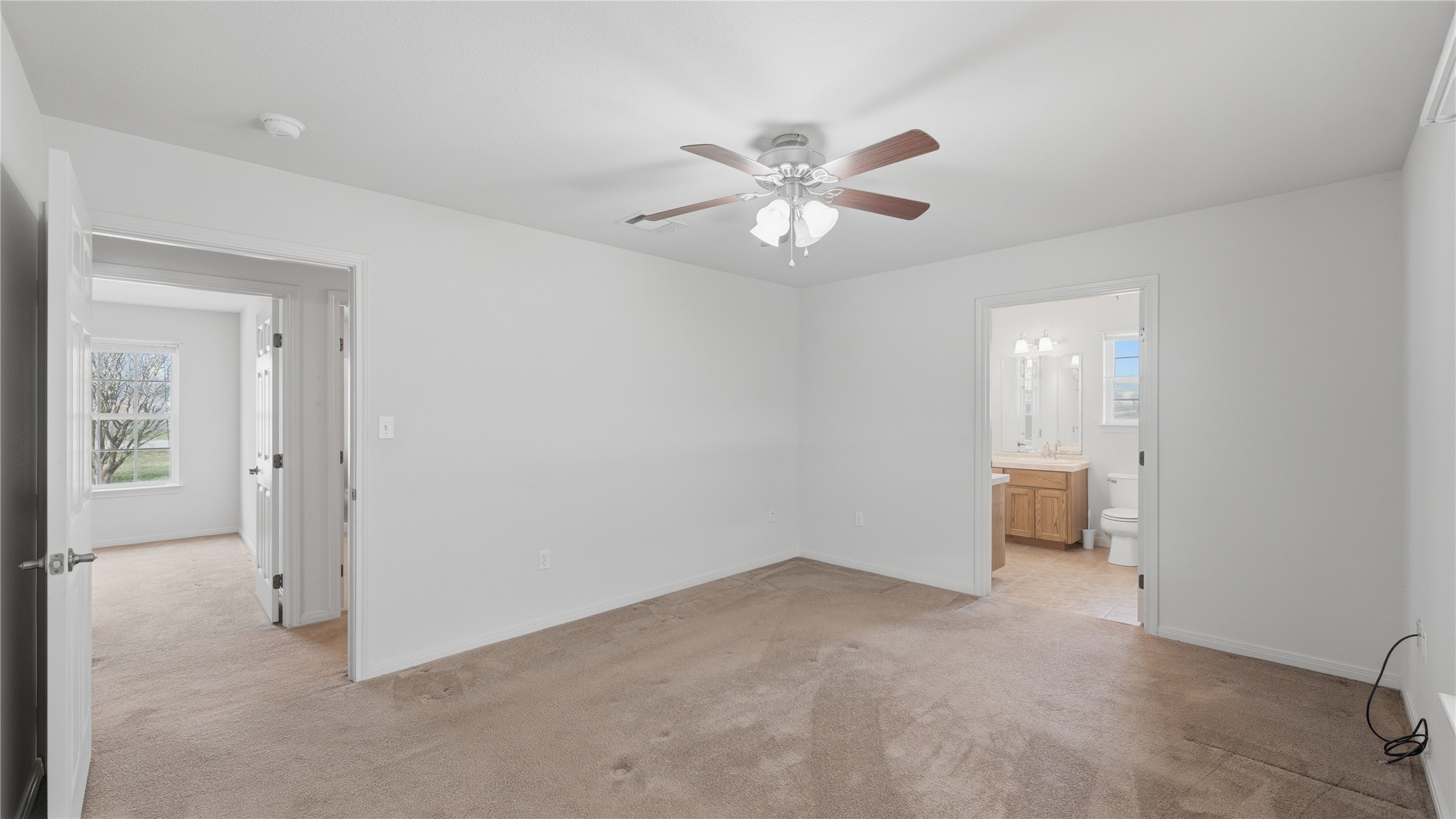 369 Young School House Road Smithville, TX 78957 - Photo 13 of 30 Unfurnished bedroom featuring light colored carpet, ceiling fan, and connected bathroom