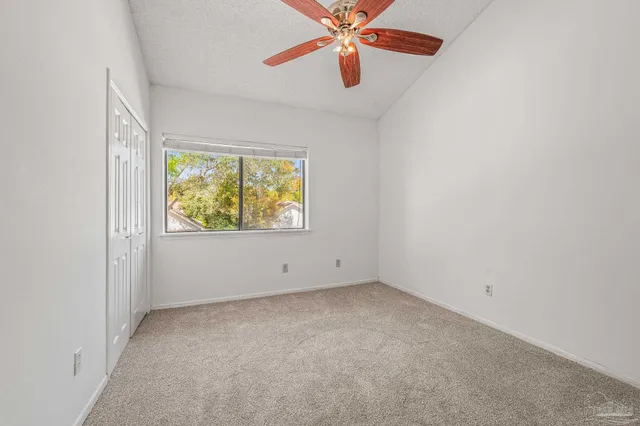 an empty room with window and ceiling fan