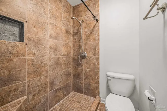 a white toilet sitting next to a shower
