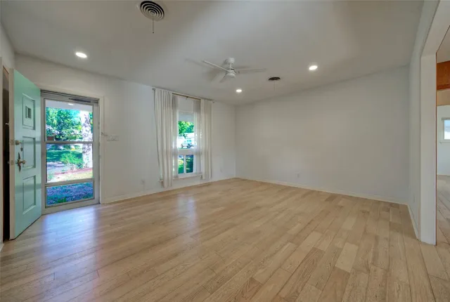 an empty room with wooden floor and windows