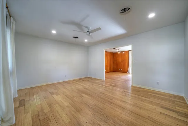 an empty room with wooden floor and natural light